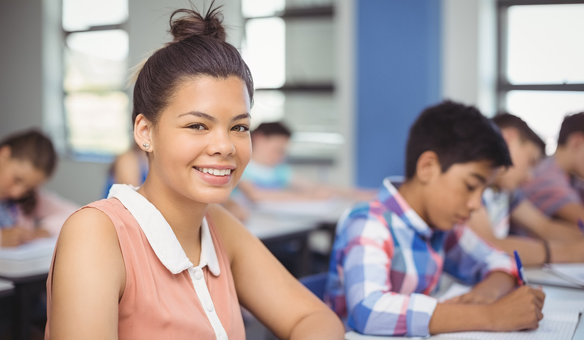 Portrait of schoolgirl sitting at desk in classroom